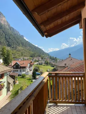 a balcony with a view of a town and mountains at Casa Fiemme Panchià in Panchia