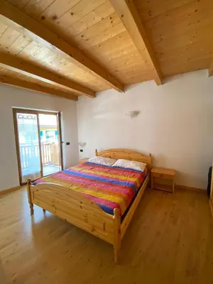 a bedroom with a bed in a room with wooden ceilings at Casa Fiemme Panchià in Panchia