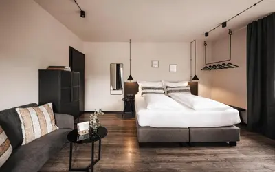 a bedroom with a large bed and a couch at Hotel Löwenhof in Bressanone