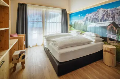 a bedroom with a large bed with a painting on the wall at Plang Farmhouse in San Cassiano