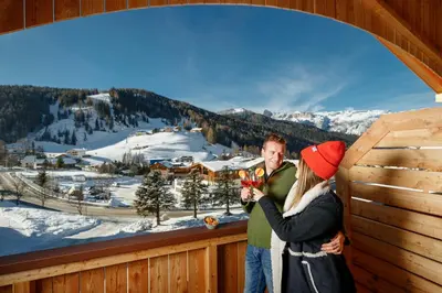 a man and a woman standing on a balcony in the snow at Plang Farmhouse in San Cassiano
