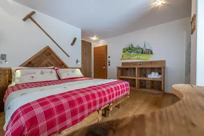 a bedroom with a bed with a red and white blanket at Garnì Ladin in Vigo di Fassa