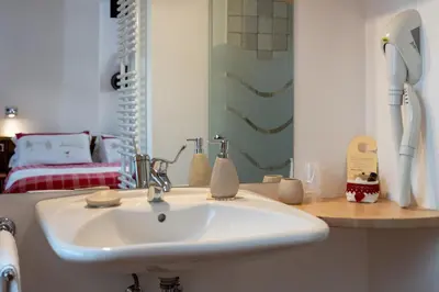 a white sink in a bathroom with a bedroom at Garnì Ladin in Vigo di Fassa