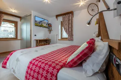 a bedroom with a bed with a red and white blanket at Garnì Ladin in Vigo di Fassa