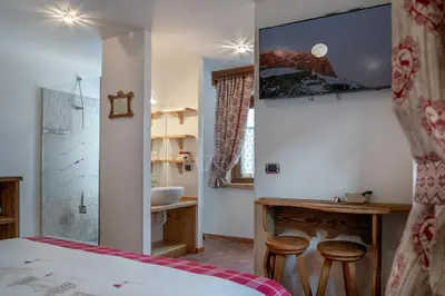 a bedroom with a bed and a bathroom with a sink at Garnì Ladin in Vigo di Fassa