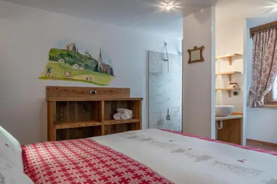 a bedroom with a bed and a bathroom with a sink at Garnì Ladin in Vigo di Fassa