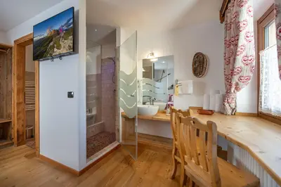 a bathroom with a sink and a vanity with a mirror at Garnì Ladin in Vigo di Fassa