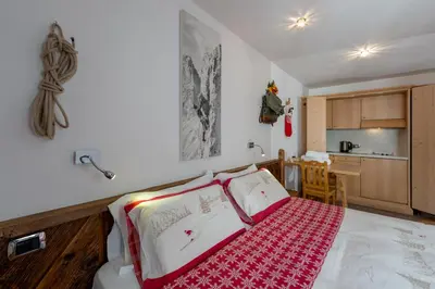 a bedroom with a bed with a red and white blanket at Garnì Ladin in Vigo di Fassa