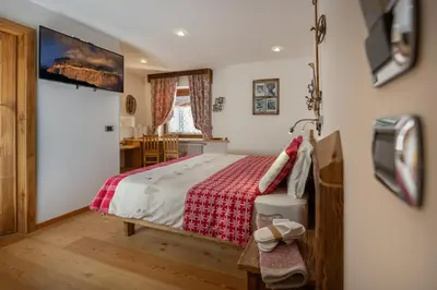 a bedroom with a bed with a red and white blanket at Garnì Ladin in Vigo di Fassa