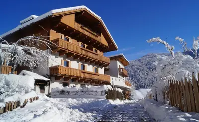 a building covered in snow with a fence at THALERHOF Onach Dolomites - Kronplatz in San Lorenzo di Sebato