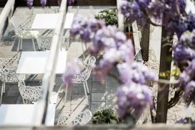 a group of tables and chairs with purple flowers at Designhotel Gius La Residenza in Caldaro