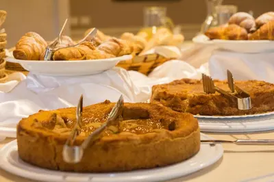 a table topped with pies and other pastries on plates at GH Hotel Piaz in Pozza di Fassa