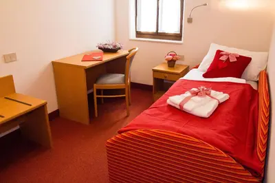 a hotel room with a bed with red sheets and a desk at GH Hotel Piaz in Pozza di Fassa