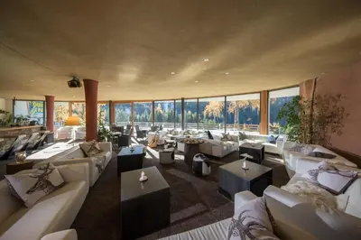 a large room with couches and tables and windows at Bike & Ski Hotel Diana Karersee in Nova Levante