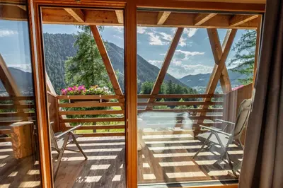 a room with a balcony with a view of mountains at Bike & Ski Hotel Diana Karersee in Nova Levante