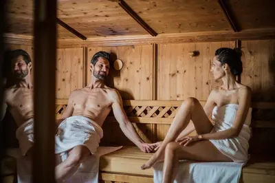 a man and woman sitting in a sauna at Hotel Fameli in Valdaora