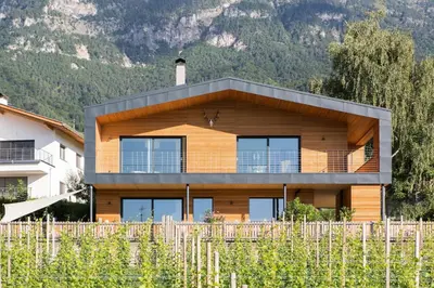 a house in the mountains behind a fence at Villa KaTo in Caldaro