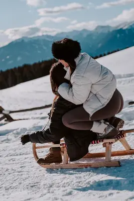 two people are sitting on a sled in the snow at Hotel Bergschlössl in Luson