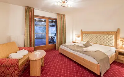 a bedroom with a large bed and a couch at Hotel Bergschlössl in Luson