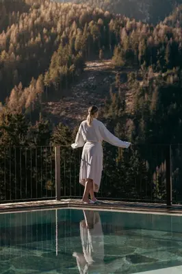 a woman in a white dress standing next to a swimming pool at Hotel Bergschlössl in Luson