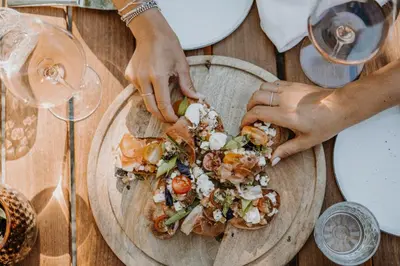 a table with two people preparing food on a wooden plate at Farmhouse Torgglerhof in Saltusio