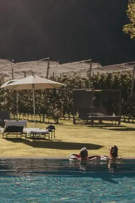 two people in a swimming pool with an umbrella at Farmhouse Torgglerhof in Saltusio