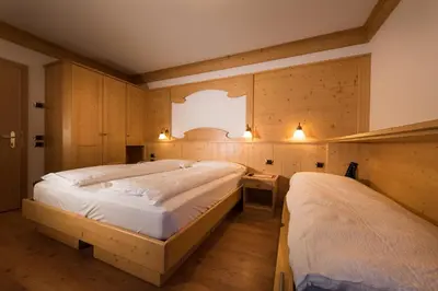 a bedroom with two beds and a window at Hotel Zirmes in Moena