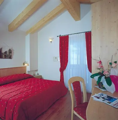 a room with a bed and a table in a room at Hotel Zirmes in Moena