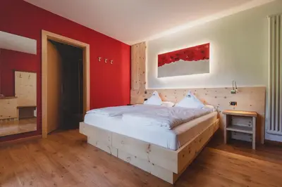 a bedroom with a large bed and a desk and a bed sidx sidx sidx sidx at Hotel Zirmes in Moena