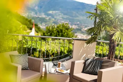 a balcony with chairs and a table with a view at Hotel Am Sonneck in Lagundo