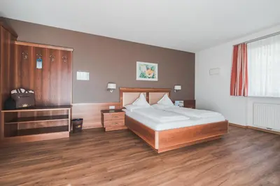 a bedroom with a large bed and wooden floors at Hotel Am Sonneck in Lagundo