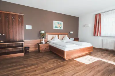 a bedroom with a large bed and wooden floors at Hotel Am Sonneck in Lagundo