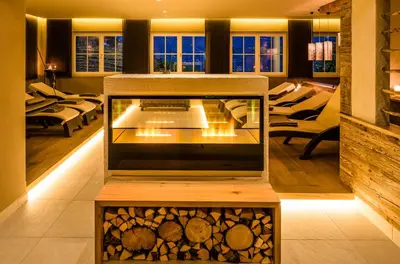 a living room with a fire place with logs in it at Hotel Am Sonneck in Lagundo