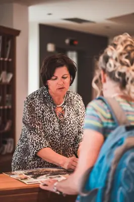 a woman sitting at a table talking to another woman at Hotel Am Sonneck in Lagundo