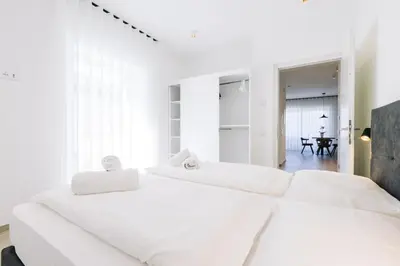 two white beds in a white bedroom with a table at Residence Martinelli in Laives