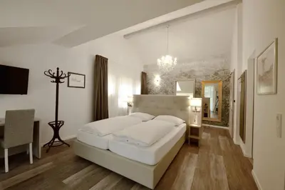 a white bedroom with a white bed and a desk at Hotel Teutschhaus in Cortina Sulla Strada Del Vino