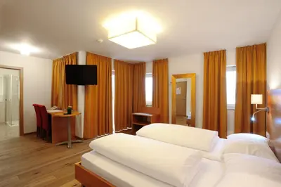 a hotel room with a white bed and a desk at Hotel Teutschhaus in Cortina Sulla Strada Del Vino