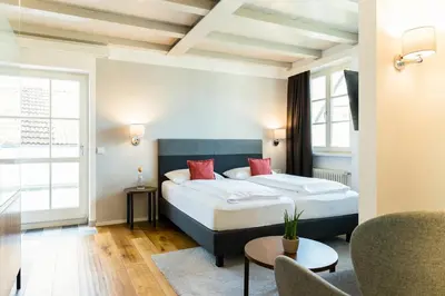 a hotel room with a large bed and a table at Hotel Teutschhaus in Cortina Sulla Strada Del Vino