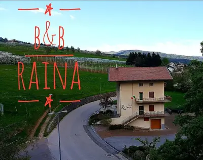 a sign that says raja ra mana next to a house at B&B RAINA in Castelfondo