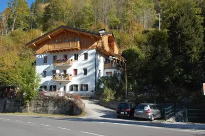a large white building with cars parked in front of it at Mountain in Alleghe