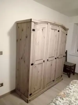 a wooden cabinet in a bedroom with a bed at Mountain in Alleghe