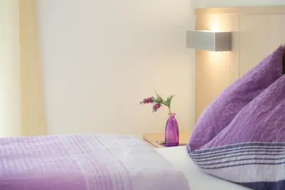 a bed with purple pillows and a vase with flowers at Grabmayrhof in Termeno