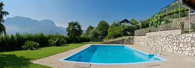 a swimming pool in a yard next to a stone wall at Grabmayrhof in Termeno