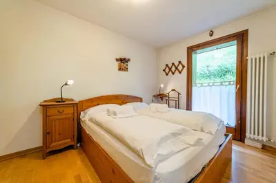 a bedroom with a bed with white sheets and a window at Dolomites Dream Arabba in Livinallongo del Col di Lana