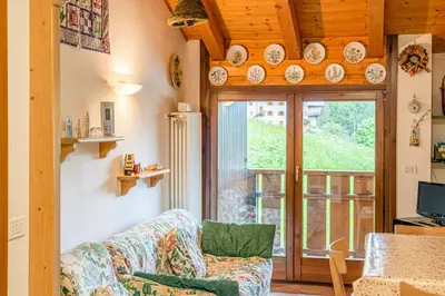 a living room with a couch and a sliding glass door at Dolomites Dream Arabba in Livinallongo del Col di Lana