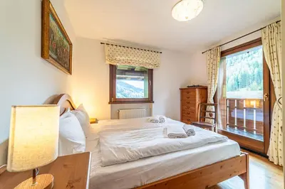 a bedroom with a bed and a lamp and a window at Dolomites Dream Arabba in Livinallongo del Col di Lana