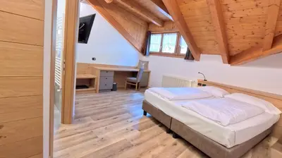 a bedroom with a bed and a desk in a room at Hotel Cristallo in Canazei