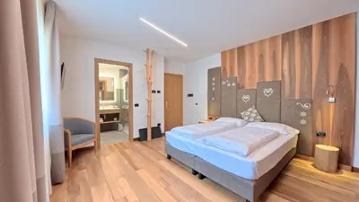 a bedroom with a bed and a chair in it at Hotel Cristallo in Canazei