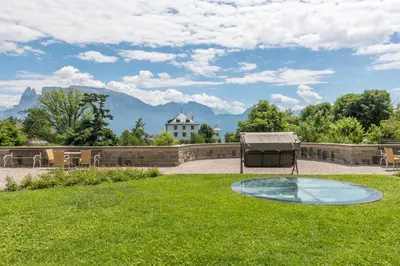 a patio with a table and chairs in the grass at Hotel Bemelmans-Post in Collalbo