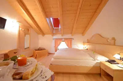 a bedroom with a bed and a table with food at Hotel Fonte Dei Veli in Panchia